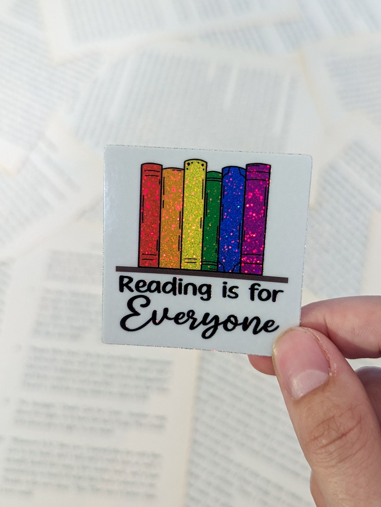 A set of 6 books sitting on a shelf, each book is a different color of the rainbow. The books are sparkly