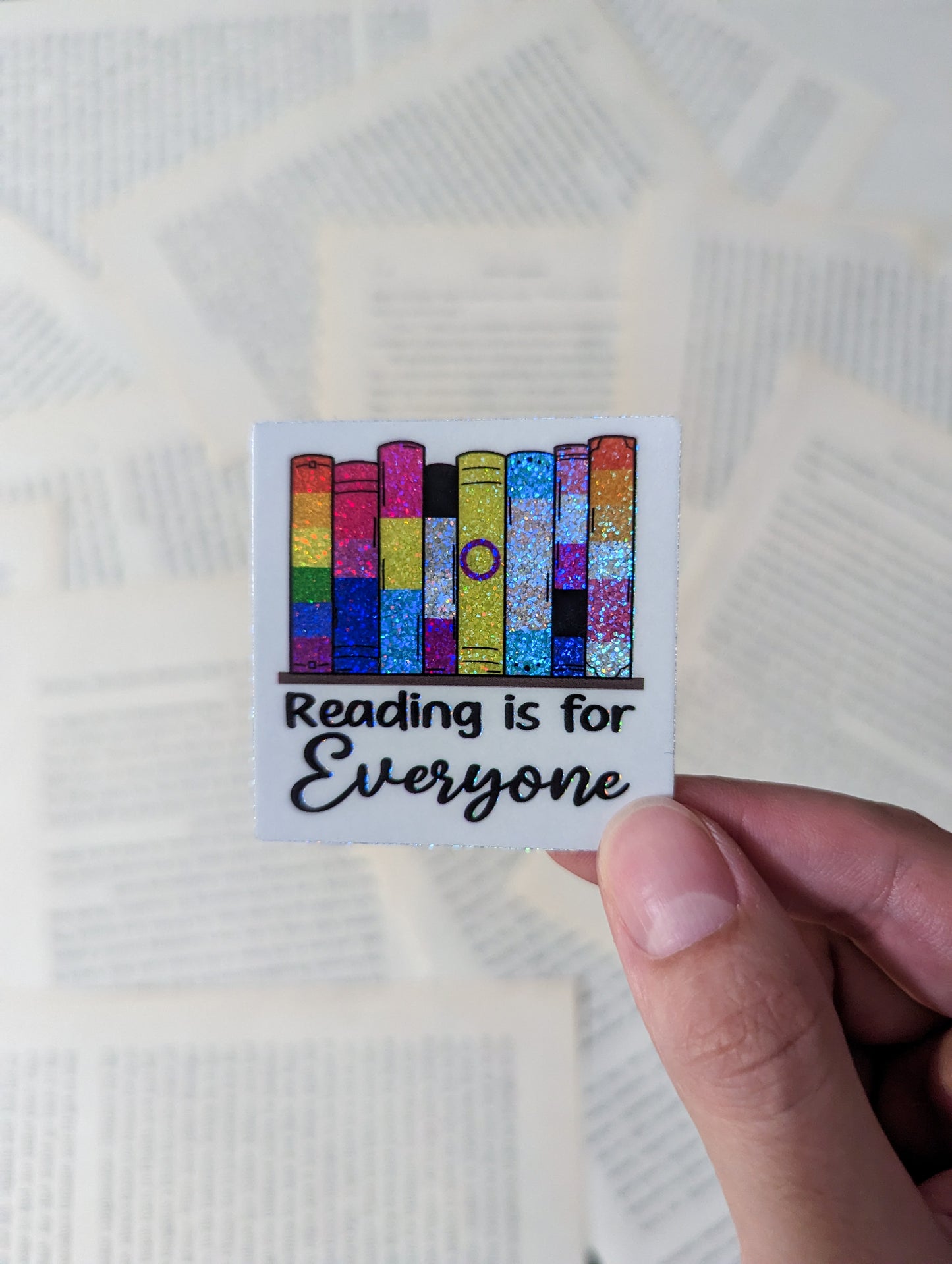 A set of 8 books sitting on a shelf. The books are each a different pride flag. From left to right Rainbow, Bisexual, Pansexual, Asexual, Intersex, Transgender, Genderfluid, Lesbian. The books are sparkly
